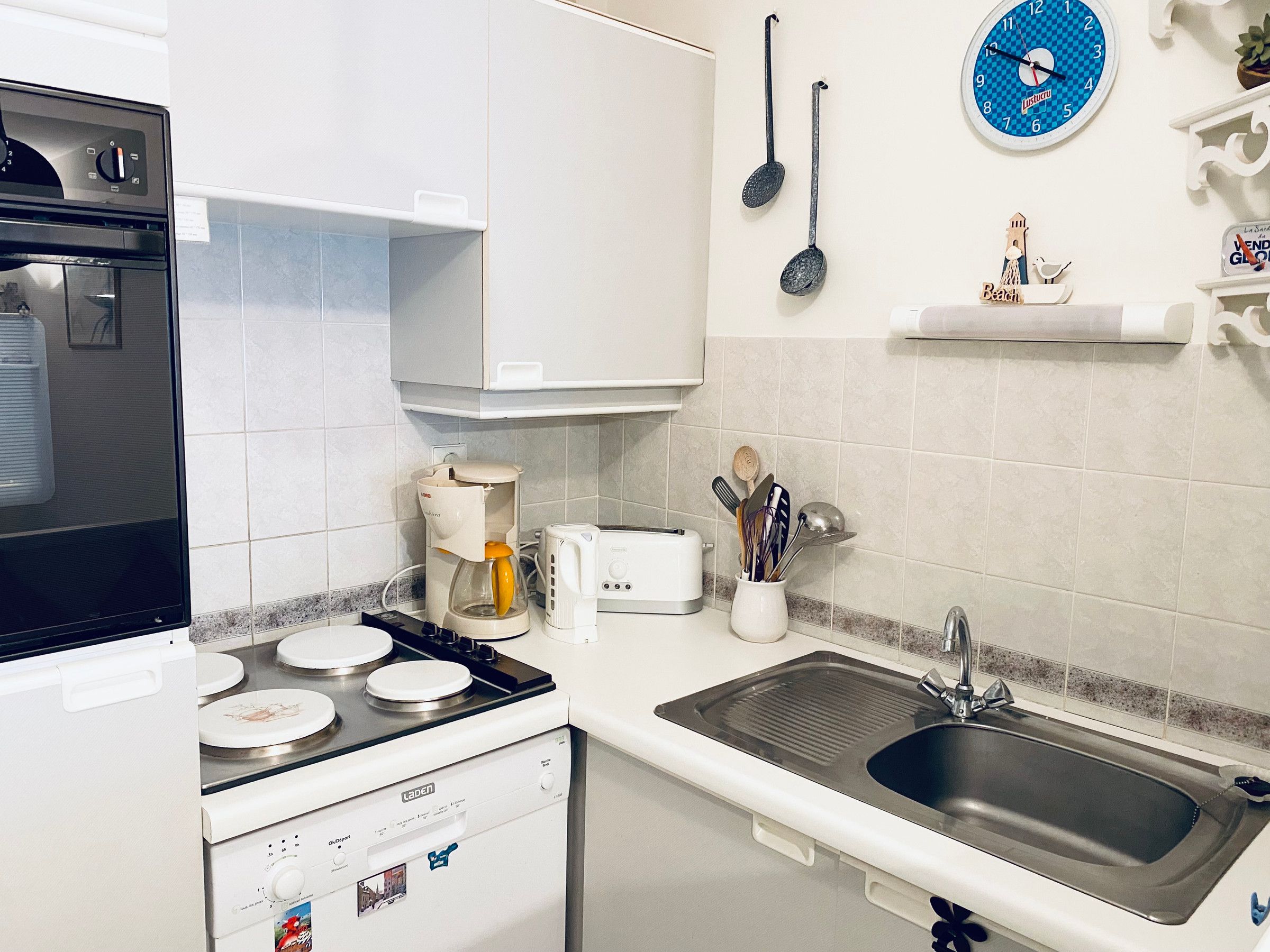 Una cocina equipada con estufa, horno, cafetera, tostadora, lavaplatos y diversos utensilios.
