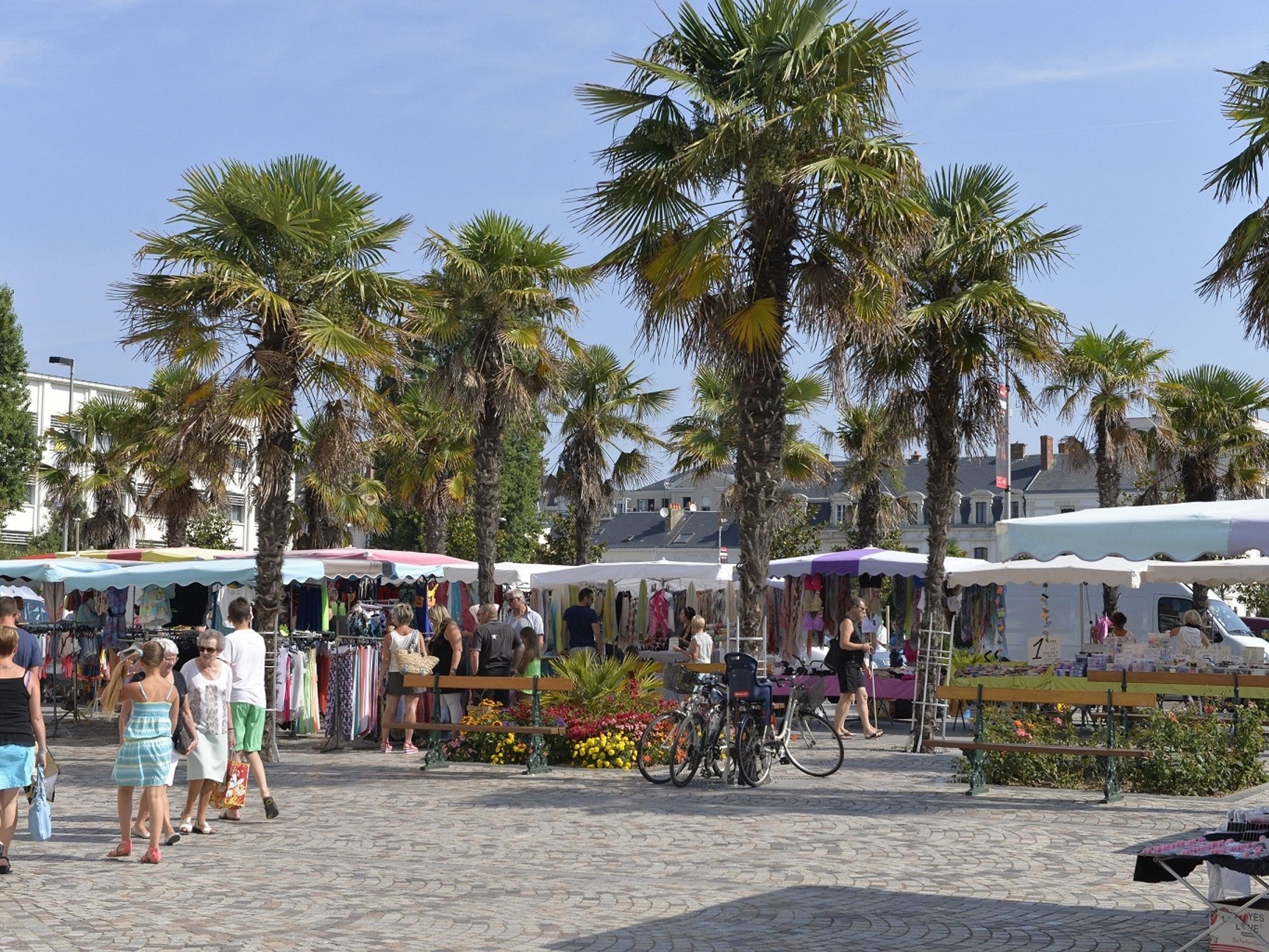 Een open markt met kraampjes en palmbomen.