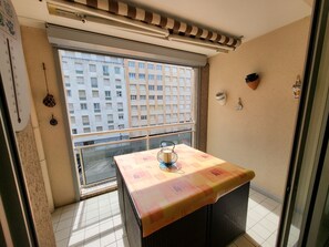 Een balkon met een tafel, een raam en uitzicht op een gebouw.