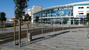 Een modern gebouw met een glazen gevel, een opvallend bord met 'Les Atlantes' en een bord met 'Casino'.