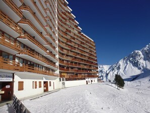 A multi-story hotel with balconies, a snowy mountain backdrop, and a clear sky. - Apartment 6 people – South balcony – At the slopes – La Mongie (La Mongie)