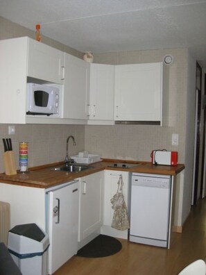 A compact kitchen with white cabinets, a microwave, a sink, a toaster, and a dishwasher. - Apartment 6 people – South balcony – At the slopes – La Mongie (La Mongie)
