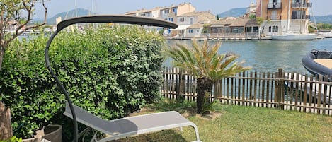 Vista al mar con valla de madera, una palmera y una silla de descanso.