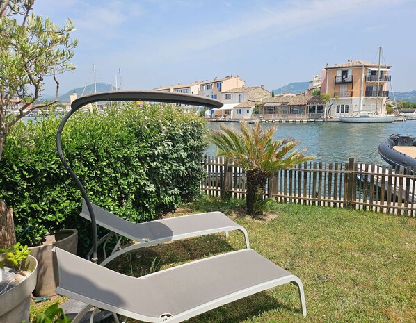 Une vue sur la mer avec une clôture en bois, un palmier et un fauteuil de jardin.