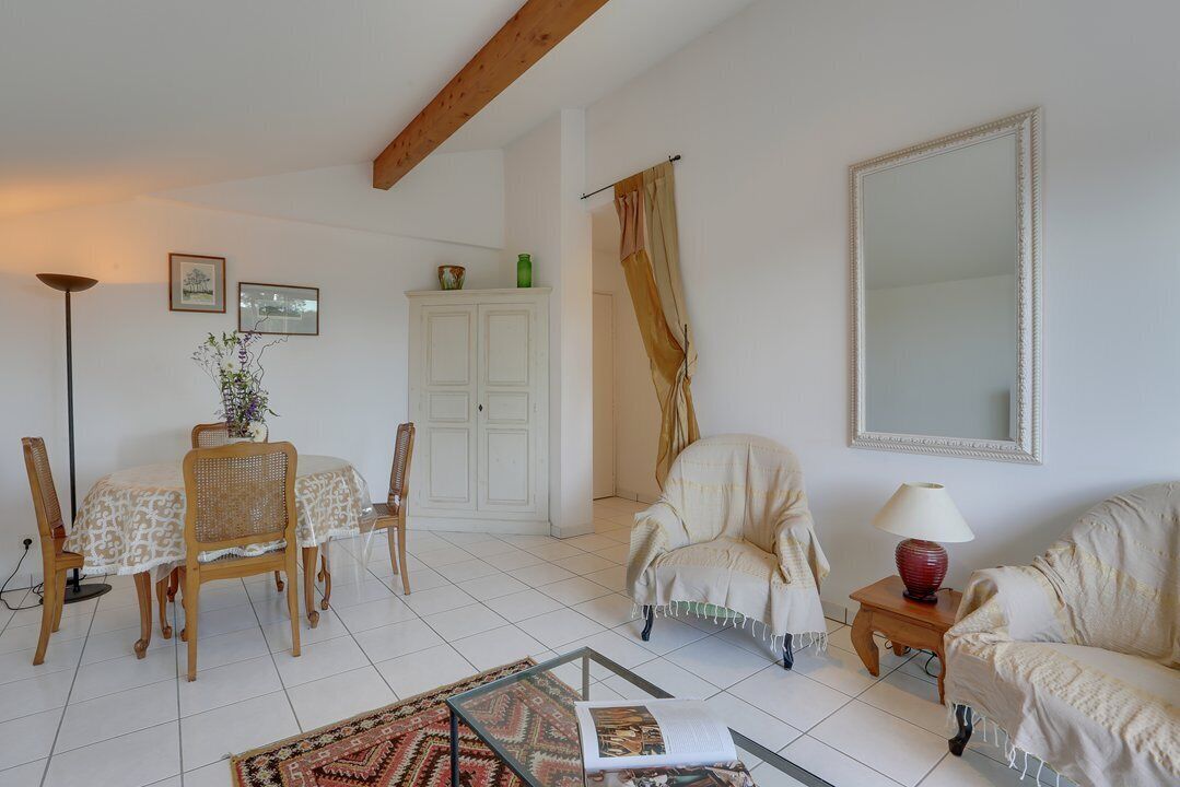 Una sala de estar con una mesa de comedor, sillas, un sofá, una mesa de centro de vidrio, una lámpara y un espejo grande.
