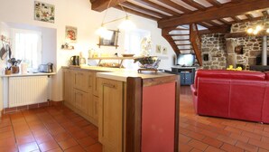 Una cocina con vigas de madera, un sofá rojo y una pared de piedra.
