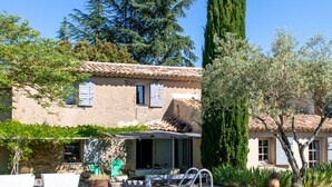 A pool area with a clear blue pool, a stone building with a tiled roof, and a tall evergreen tree. - L' OUSTAOU LES FORTUNES 3-star Provence farmhouse (Ansouis)