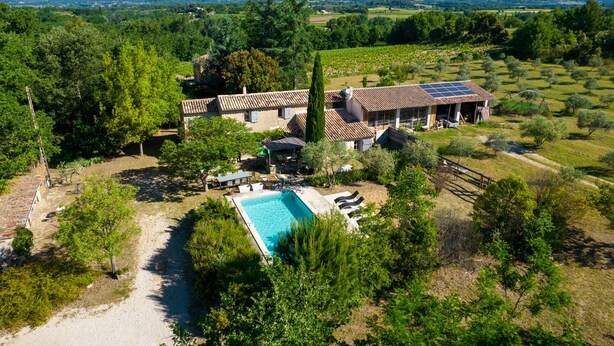 A villa with a swimming pool, surrounded by lush greenery and vineyards, with a view of distant mountains. - L' OUSTAOU LES FORTUNES 3-star Provence farmhouse (Ansouis)
