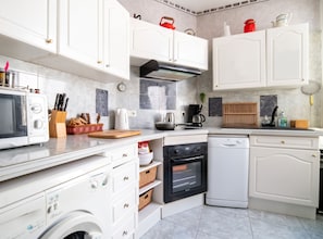 A modern kitchen with white cabinetry, a microwave, a coffee maker, and a dishwasher. - Homerez - Apt. central Saumur, city view (Saumur)