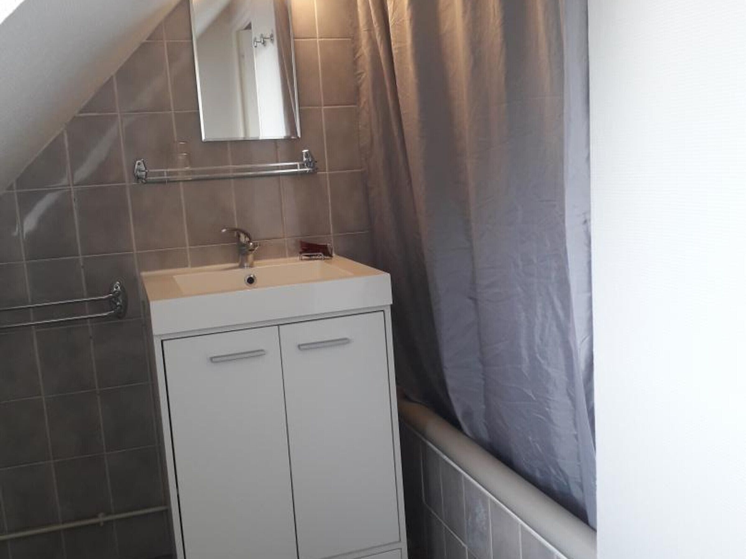A bathroom with a white vanity, a mirror, and a towel rack.