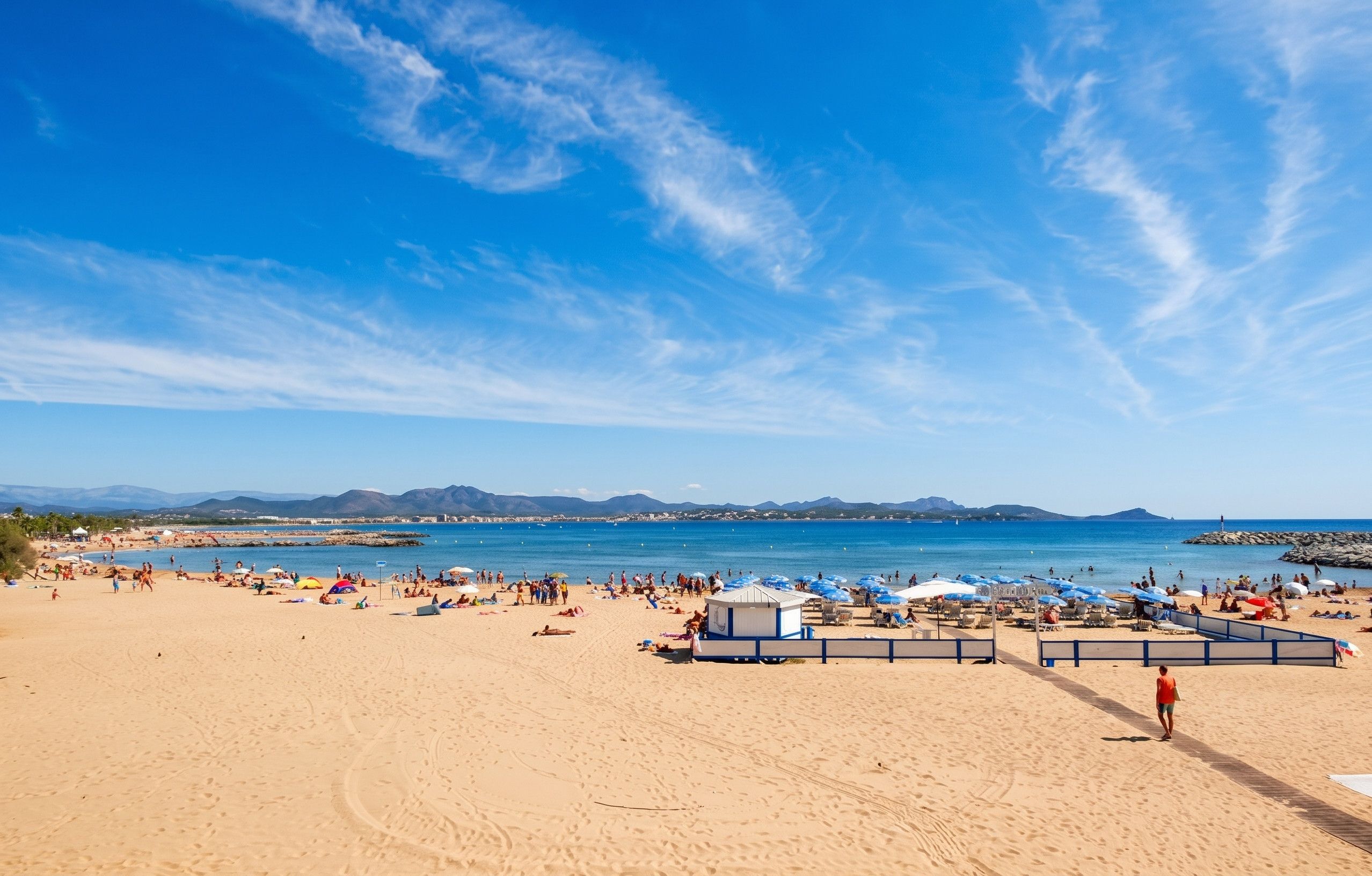 Una spiaggia con persone, ombrelloni e cielo sereno.