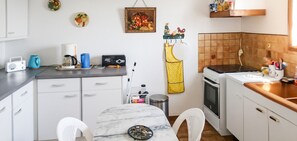 Een compacte keuken met witte kastjes, een marmeren aanrecht, een fornuis en een spoelbak.