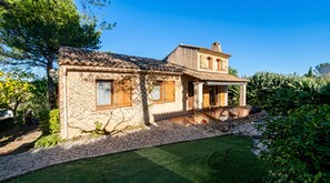 Una casa de piedra de dos pisos, con techo de tejas, un pequeño porche y un césped bien cuidado.