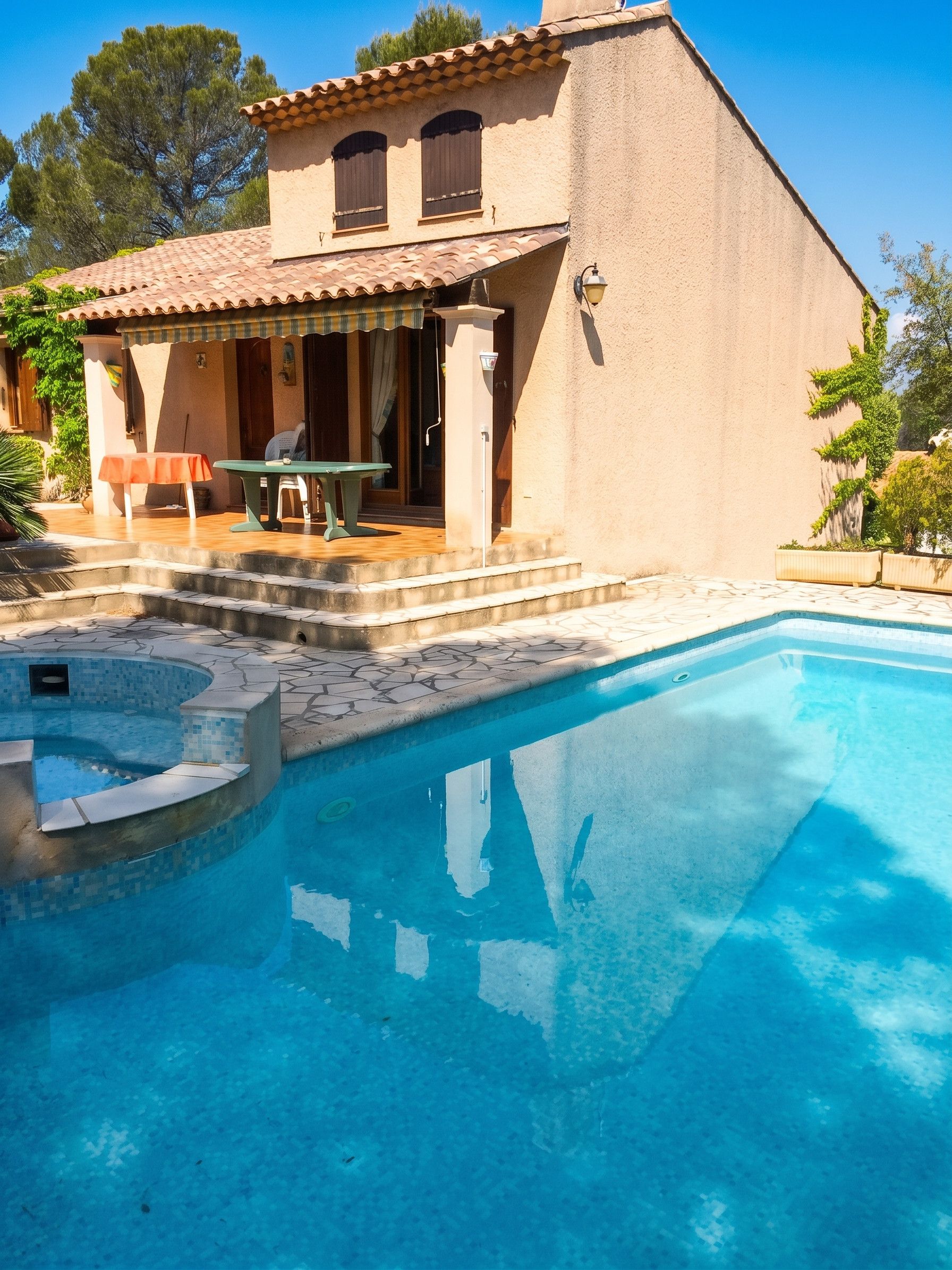 Uma casa de dois andares com piscina, móveis de exterior e um pérgula.