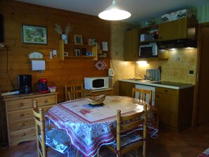 A cozy kitchen with wooden cabinets, a microwave, a toaster, and a dining table with chairs.