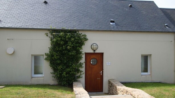 A building with a dark roof, a wooden door, and a small window on the side.