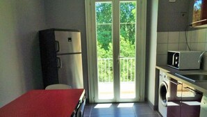 A compact kitchen with a refrigerator, microwave, and washing machine.