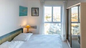 Een hotelkamer met een bed, een raam met gordijnen, een lamp en kunst aan de muur.