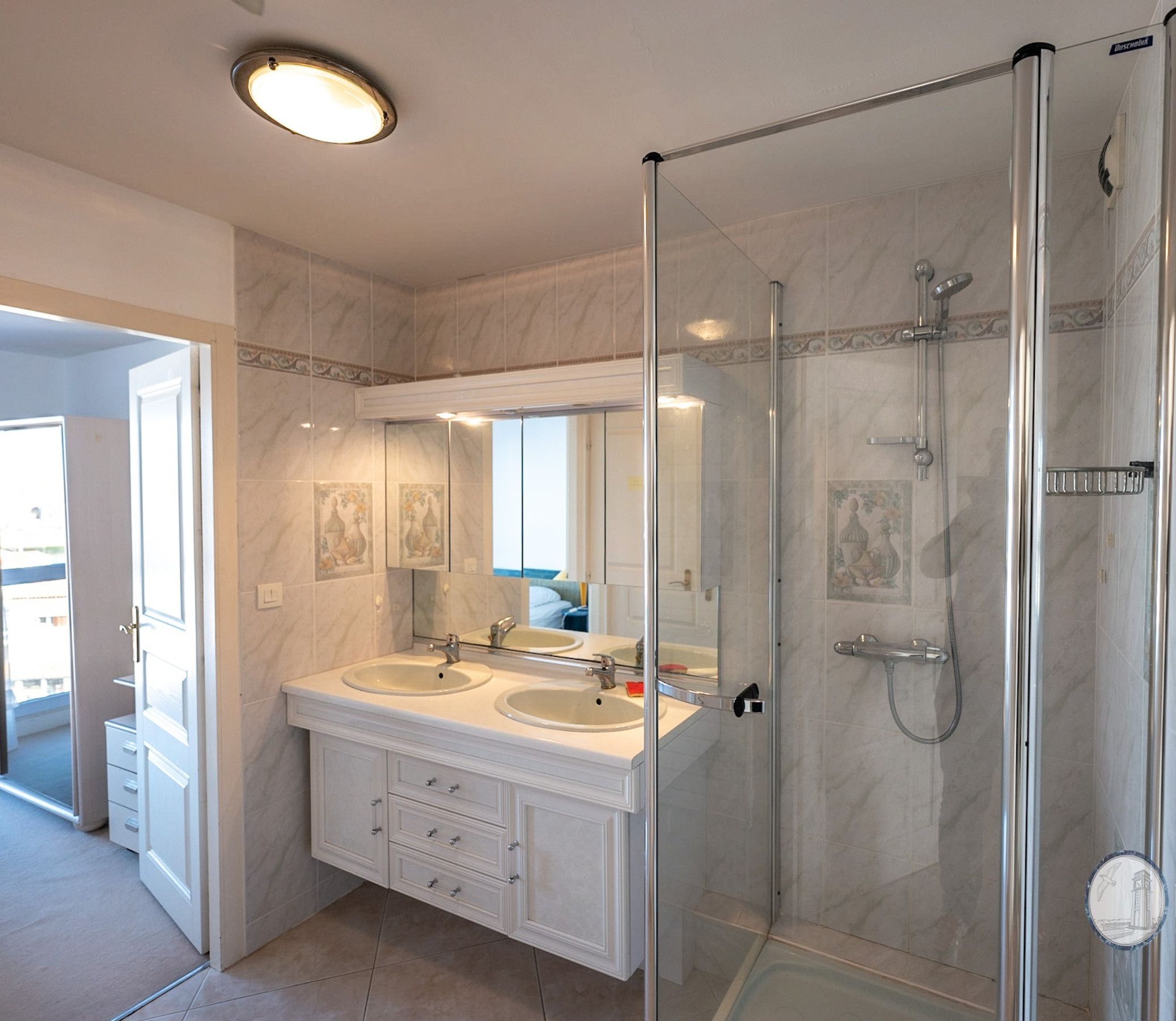 Un baño moderno con dos lavamanos, cabina de ducha de vidrio y un espejo grande.