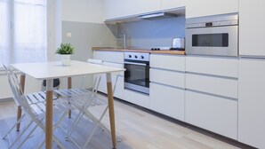 A modern kitchen with white cabinets, a built-in oven, a microwave, and a wooden countertop. - 5 min walk to the sea, the Croisette and the Palais des Festivals (Cannes)