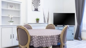 A dining area with a table covered in a polka dot tablecloth, surrounded by four chairs with wooden frames and cushioned seats. A flat-screen TV is mounted on the wall above the table. - 5 min walk to the sea, the Croisette and the Palais des Festivals (Cannes)