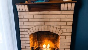 A fireplace with a brick surround and a wooden floor. - Homerez - Villa Soulac-sur-Mer (Soulac-sur-Mer)