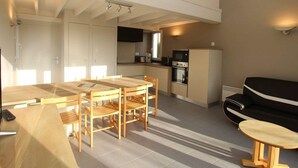 Un espacio habitable compacto con comedor, kitchenette y zona de estar.