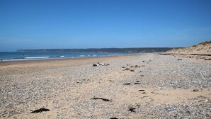 Una playa de guijarros con cielo despejado y mar tranquilo.