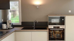Una cocina moderna con horno empotrado, cafetera y fregadero.
