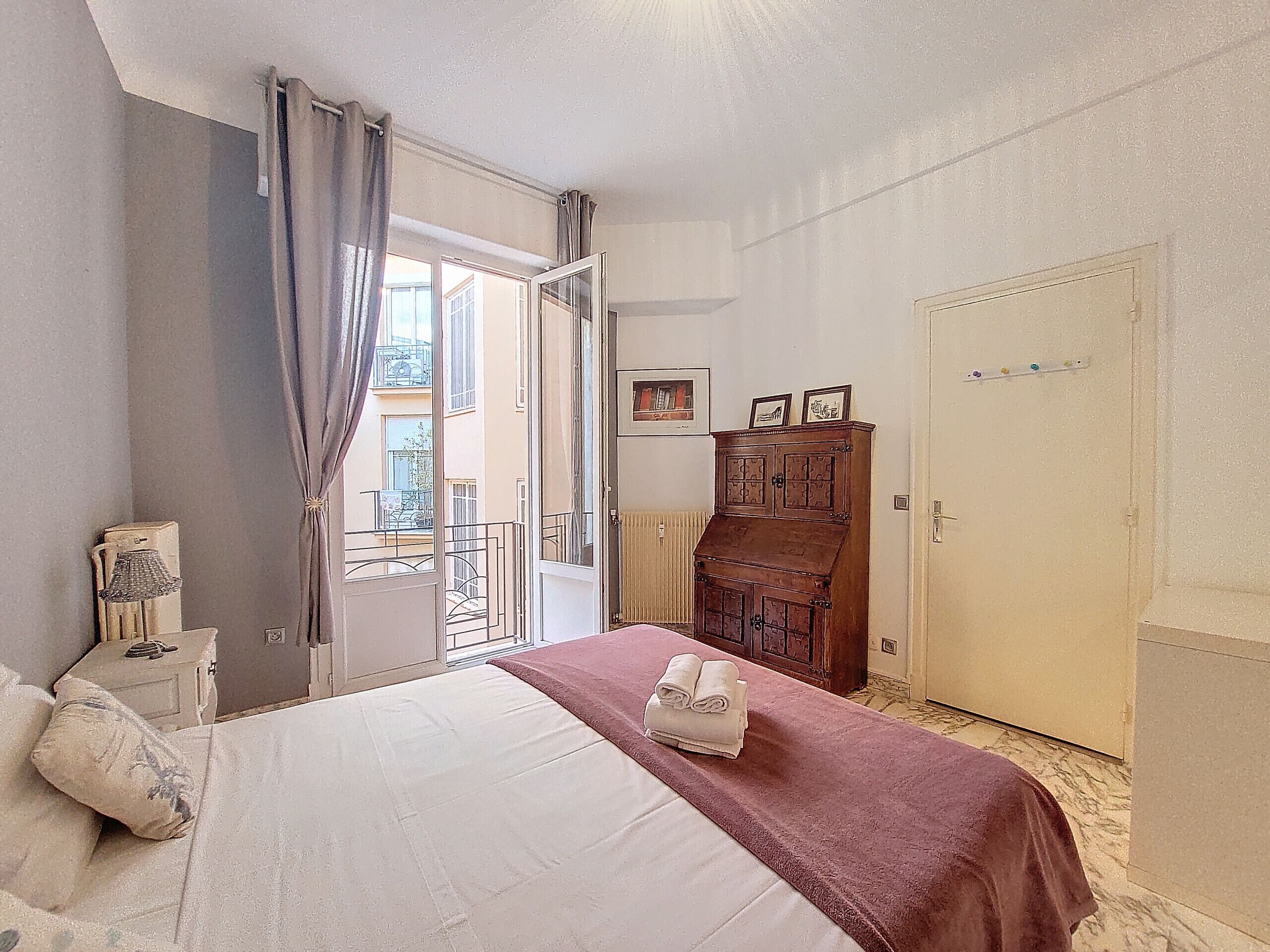 A bedroom with a bed, a wooden cabinet, a radiator, and a door.