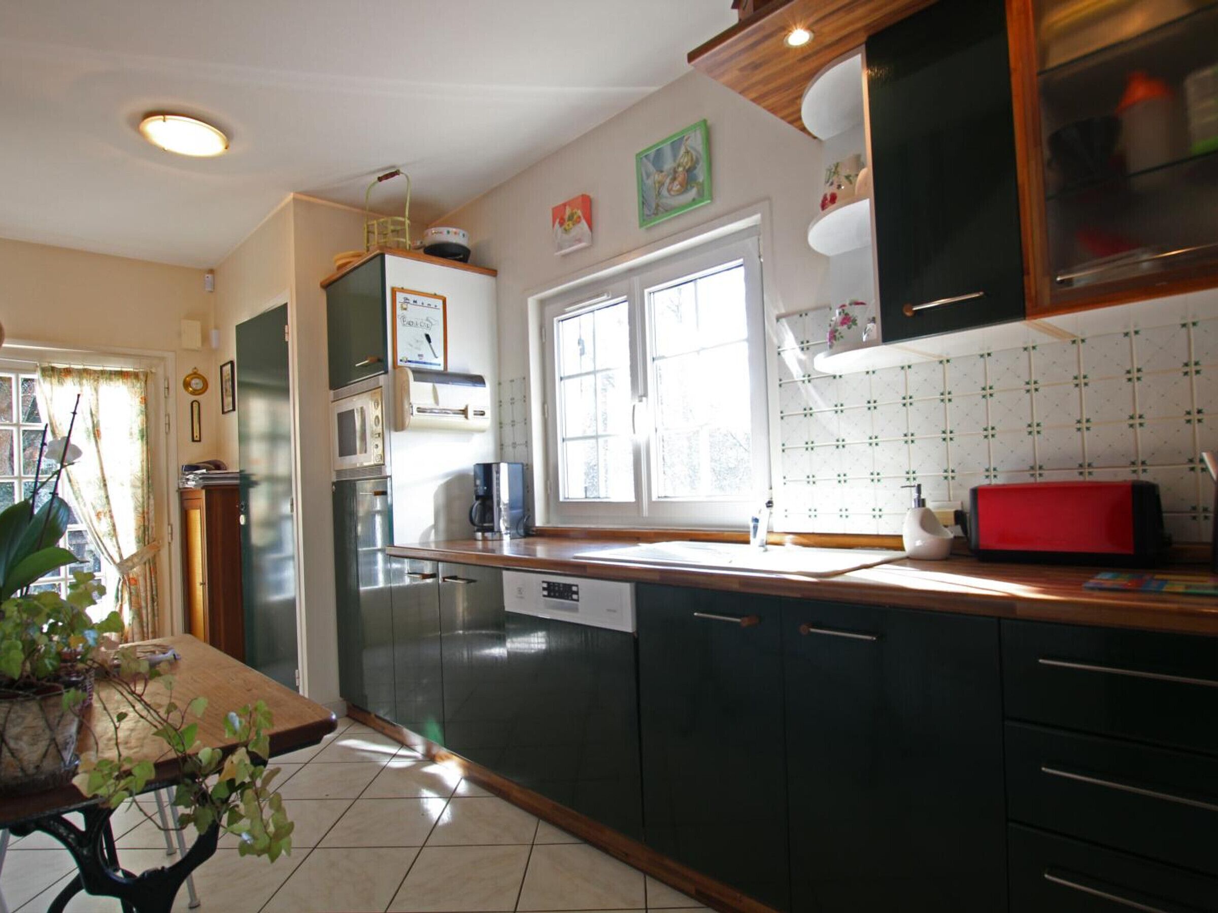 A kitchen with dark cabinets, a window, a sink, and a red toaster.