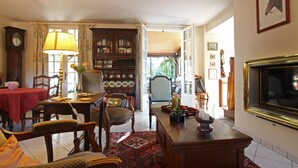 Een gezellige woonkamer met een open haard, een televisie, een boekenkast en een eethoek met een tafel en stoelen.