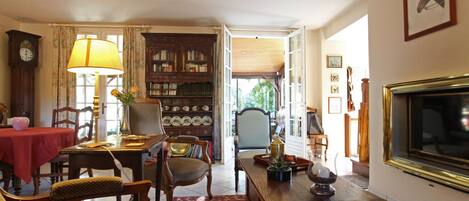 A cozy living room with a fireplace, a television, a bookshelf, and a dining area with a table and chairs.