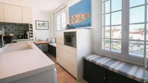 Eine moderne Küche mit weißen Schränken, einer eingebauten Mikrowelle und einem großen Fenster mit Blick auf Gebäude.