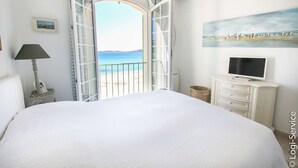 Ein Schlafzimmer mit einem großen Bett, einem Fernseher auf einer Kommode und einem Gemälde an der Wand.