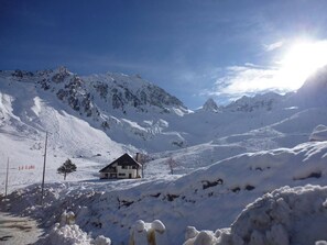 Eine verschneite Berglandschaft mit einem einzelnen Haus im Vordergrund.