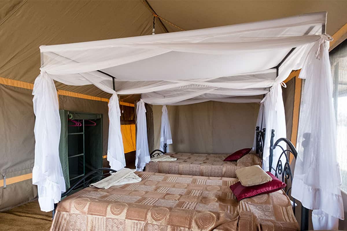 Une pièce aménagée comme une tente, avec deux lits, chacun surmonté d’un dais. On peut voir une armoire et un fauteuil suspendu.