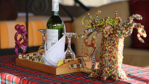 A table with a bottle of wine, a glass, and a decorative item on a plaid tablecloth. - Serengeti Wild Camps (Serengeti)