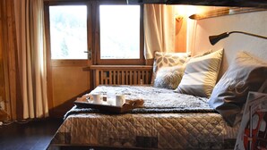 A cozy bedroom with a wooden bed, a fluffy white ottoman, and a tray with two mugs. - 2-room apartment for 5 at Méribel slopes (Méribel)