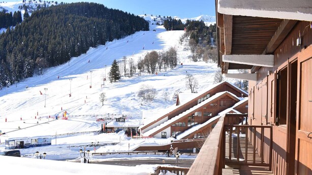 A wooden building with a balcony overlooking a snowy ski slope. - 2-room apartment for 5 at Méribel slopes (Méribel)