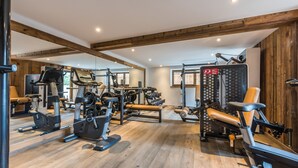 Un gimnasio con diversos equipos de ejercicio, vigas de madera en el techo y un espejo grande.