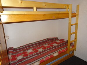 A bunk bed with a wooden frame, a ladder, and a striped blanket.