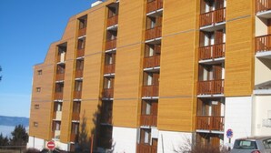 Un edificio de varios pisos con un diseño moderno, que cuenta con balcones en cada nivel.