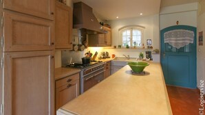 Una cocina con armarios de madera, estufa, lavamanos y un tazón verde sobre la encimera.