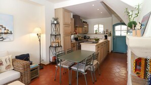 Una cocina acogedora con zona de comedor, una puerta azul y suelo de baldosas.