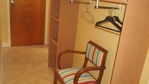 A compact room with a wooden chair, a coat rack with hangers, and a door.