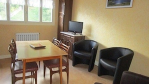 A dining area with a table and chairs, a television, and a framed picture on the wall.