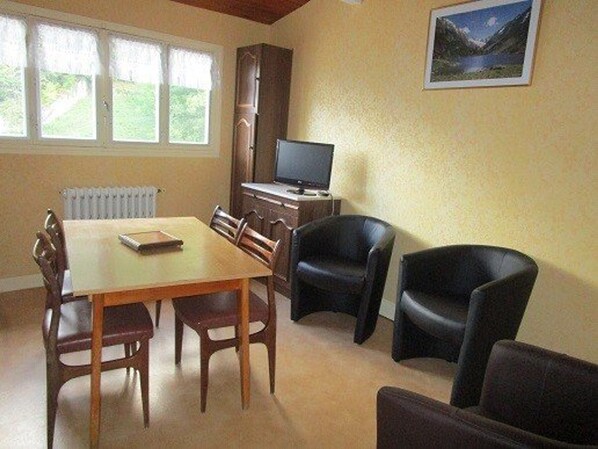 Un comedor con una mesa, sillas, un televisor y un cuadro en la pared.