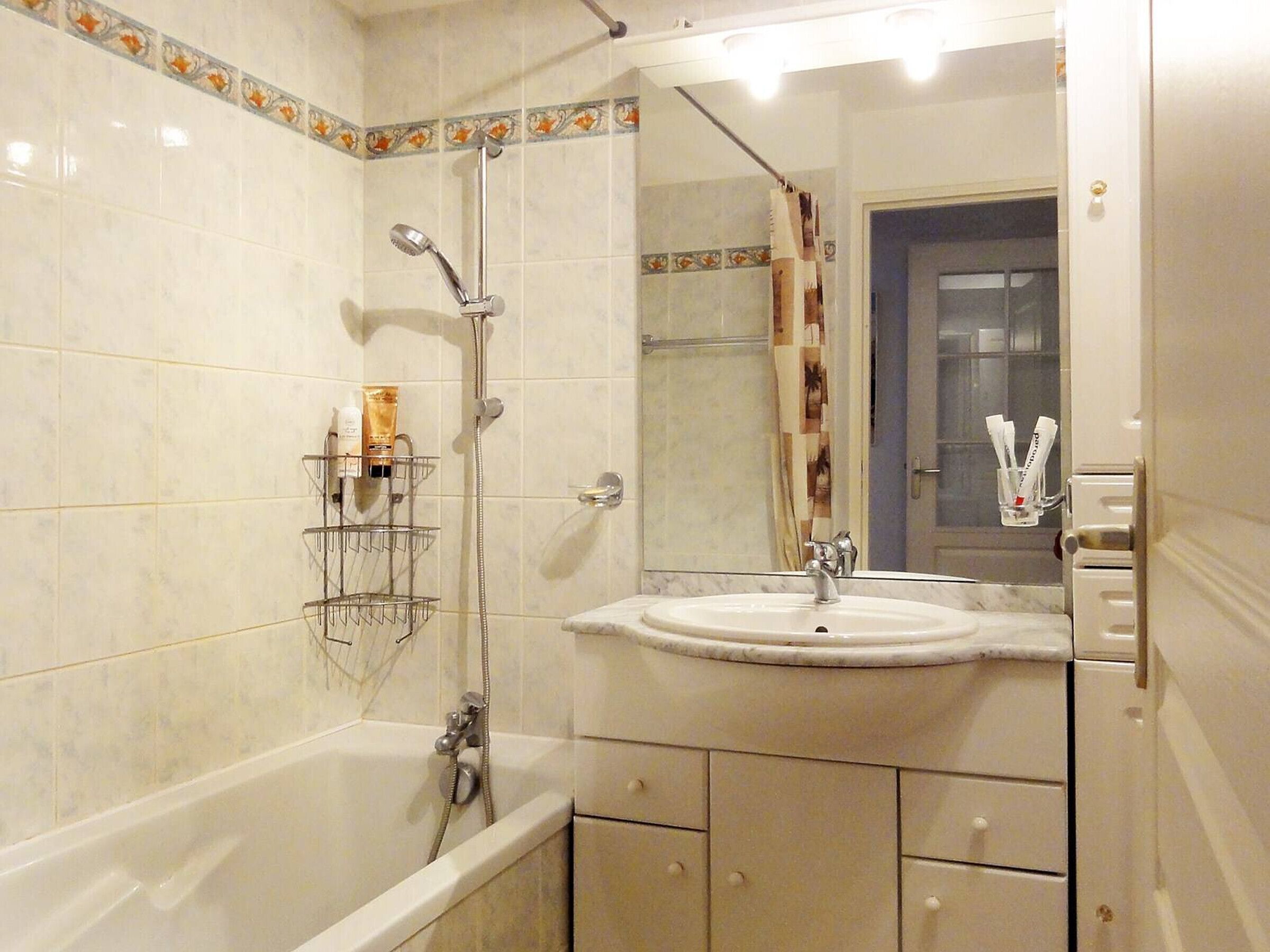 A bathroom with a bathtub, a sink, and a shower. There are toiletries on the wall and a towel rack.