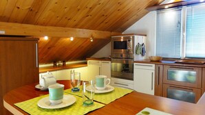 A kitchen with wooden ceiling beams, a built-in oven, and a window with blinds. - Beautiful 67m² apartment, 2 bedrooms, parking, south-facing balcony - Briançon (Briançon)